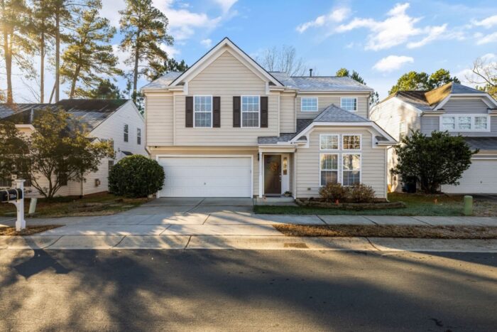 A Home With Cream Siding White Trim And Brown Shutters