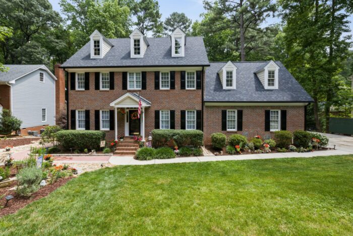 A brick house has a large addition off the side for added space.