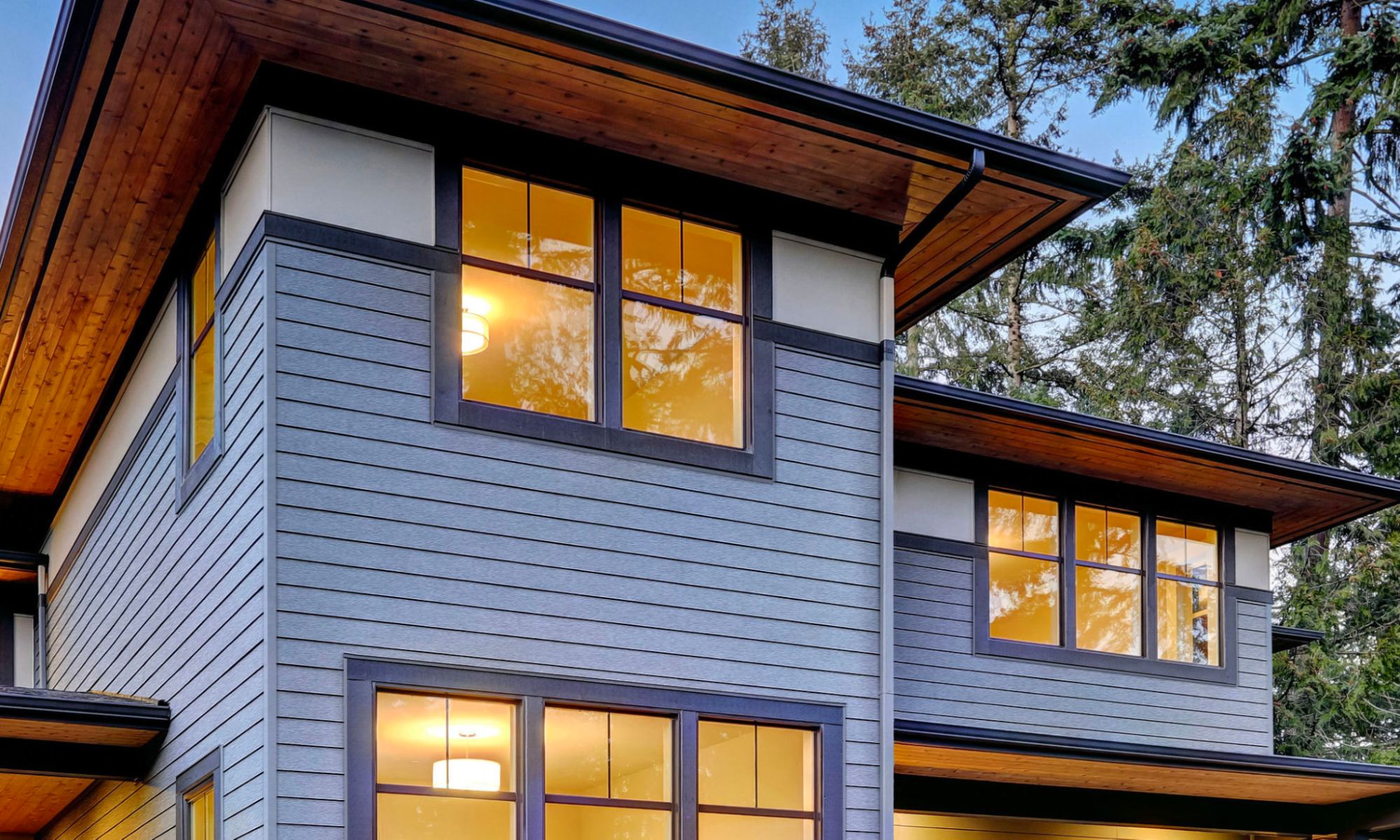 This image depicts a home with steel siding and a warmly lit interior.