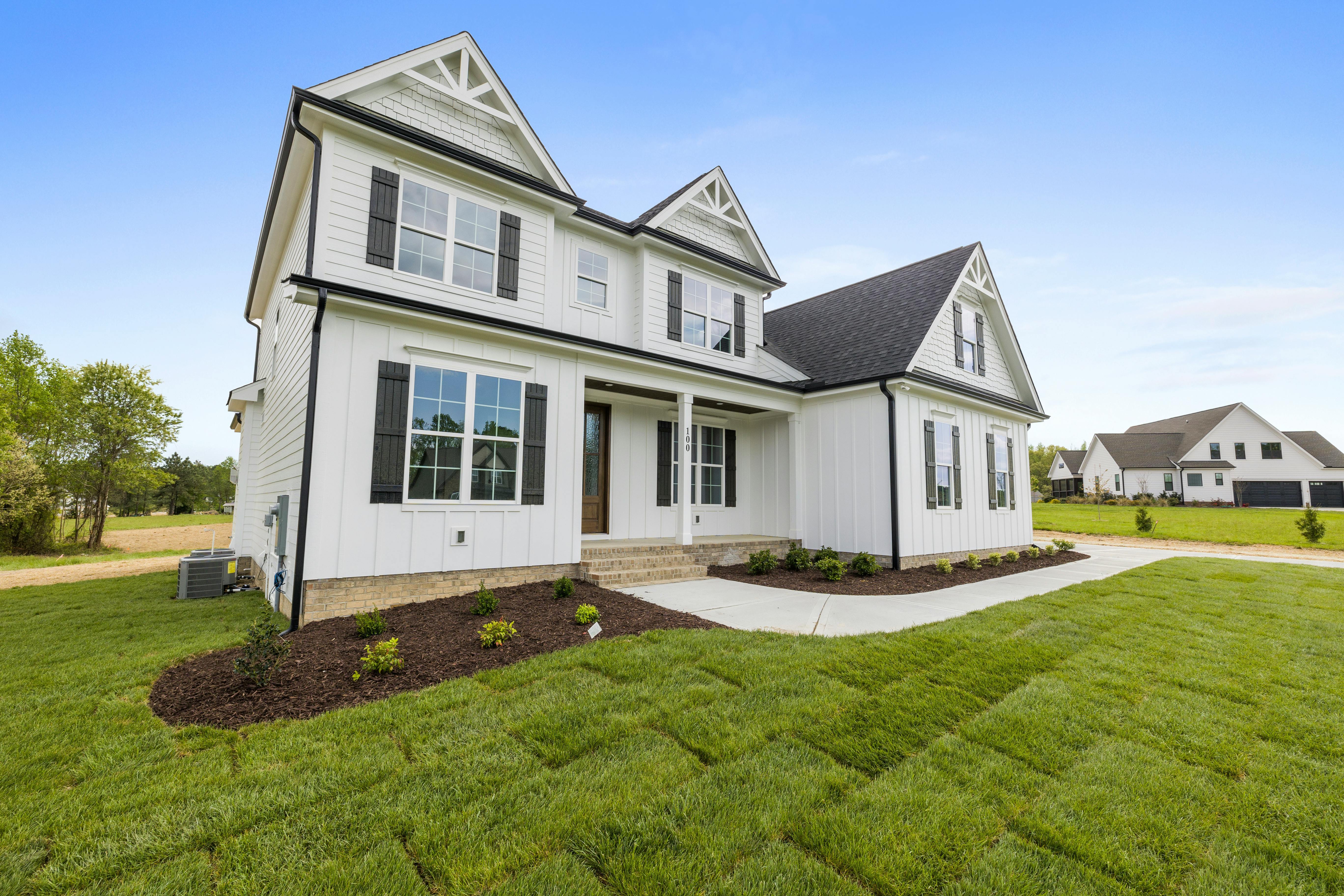 This image depicts a white home with board-and-batten accents and black shutters.