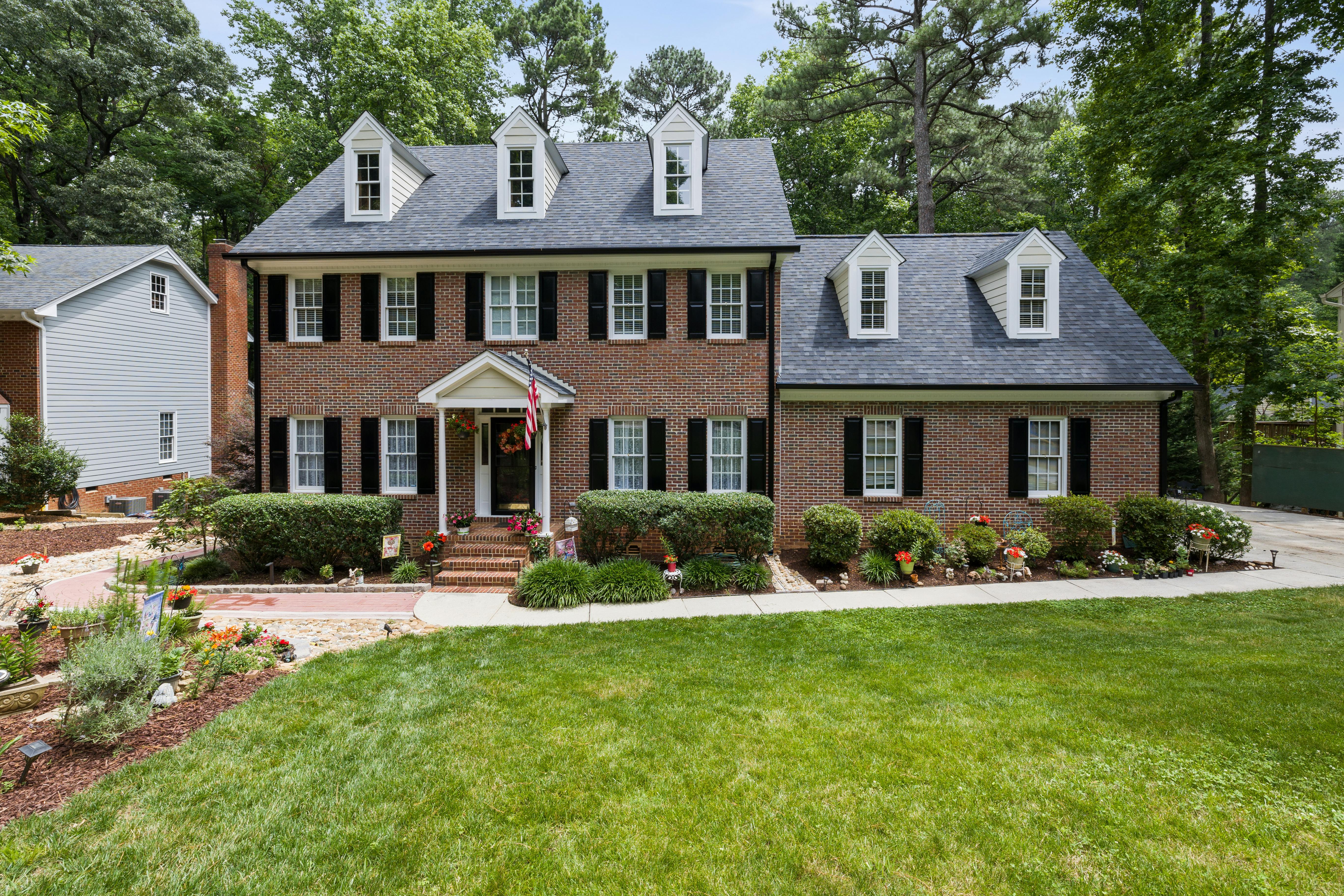 A brick house has a large addition off the side for added space.