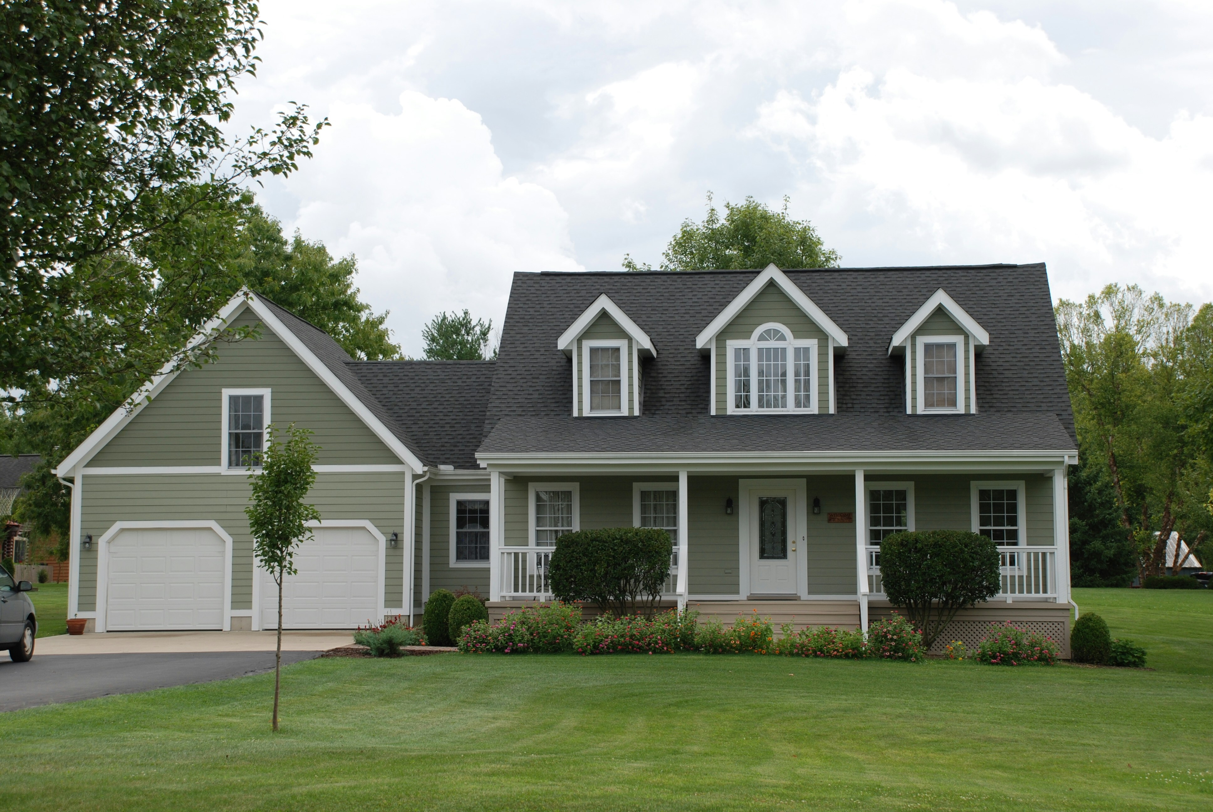 A charming two-story home has green horizontal vinyl siding and white trim.